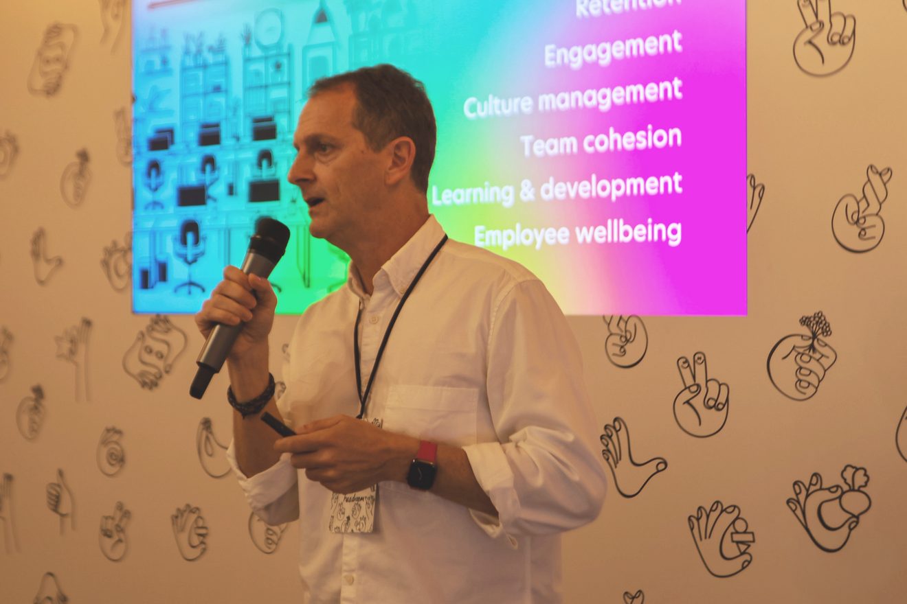 Sean Keogh speaking into a microphone in front of a presentation